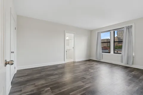 a view of an empty room with wooden floor and windows