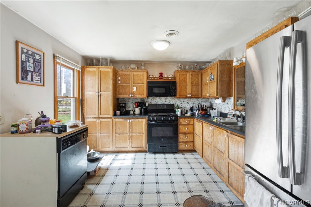 8442 Wheeling Road Mechanicsville, VA 23116 - Photo 3 of 23 a kitchen with a sink a stove a refrigerator and black cabinets next to a window