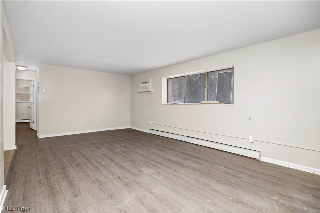 5382 Lee Road, Unit 102 Maple Heights, OH 44137 - Photo 4 of 25 Empty room featuring baseboard heating, wood finished floors, and a baseboard radiator