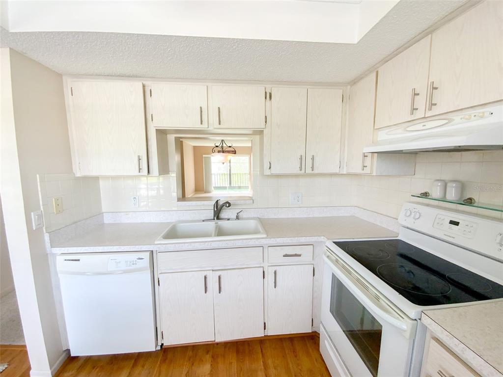 1370 Heather Ridge Boulevard, Unit 204 Dunedin, FL 34698 - Photo 3 of 37 a kitchen with white cabinets white appliances sink and dishwasher