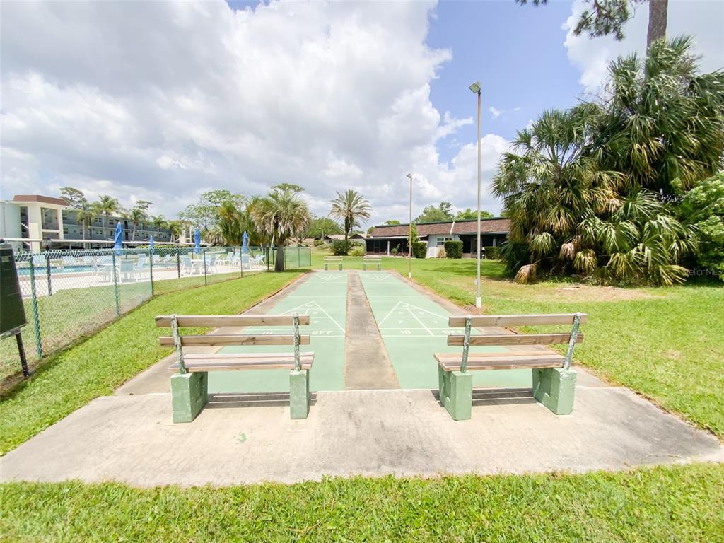 1370 Heather Ridge Boulevard, Unit 204 Dunedin, FL 34698 - Photo 36 of 37 a park view with a bench and garden