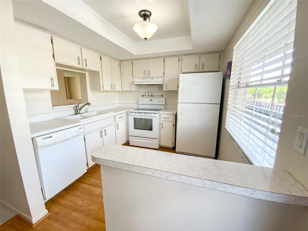 1370 Heather Ridge Boulevard, Unit 204 Dunedin, FL 34698 - Photo 4 of 37 a kitchen with white cabinets and white appliances