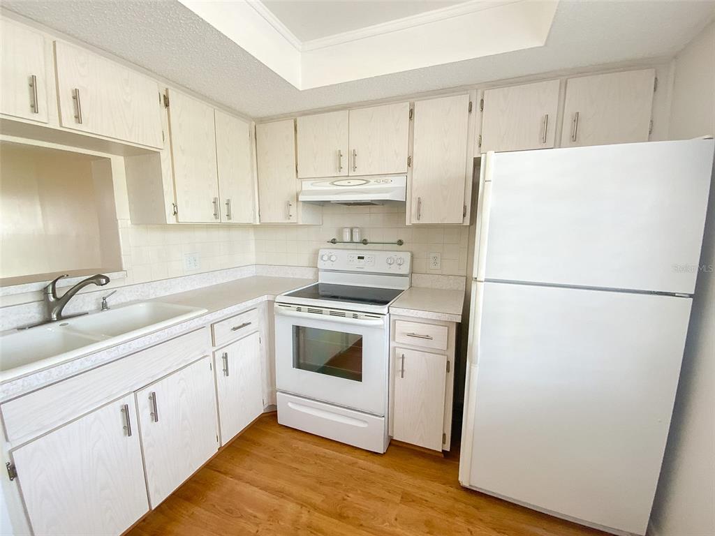 1370 Heather Ridge Boulevard, Unit 204 Dunedin, FL 34698 - Photo 5 of 37 a kitchen with white cabinets and white appliances