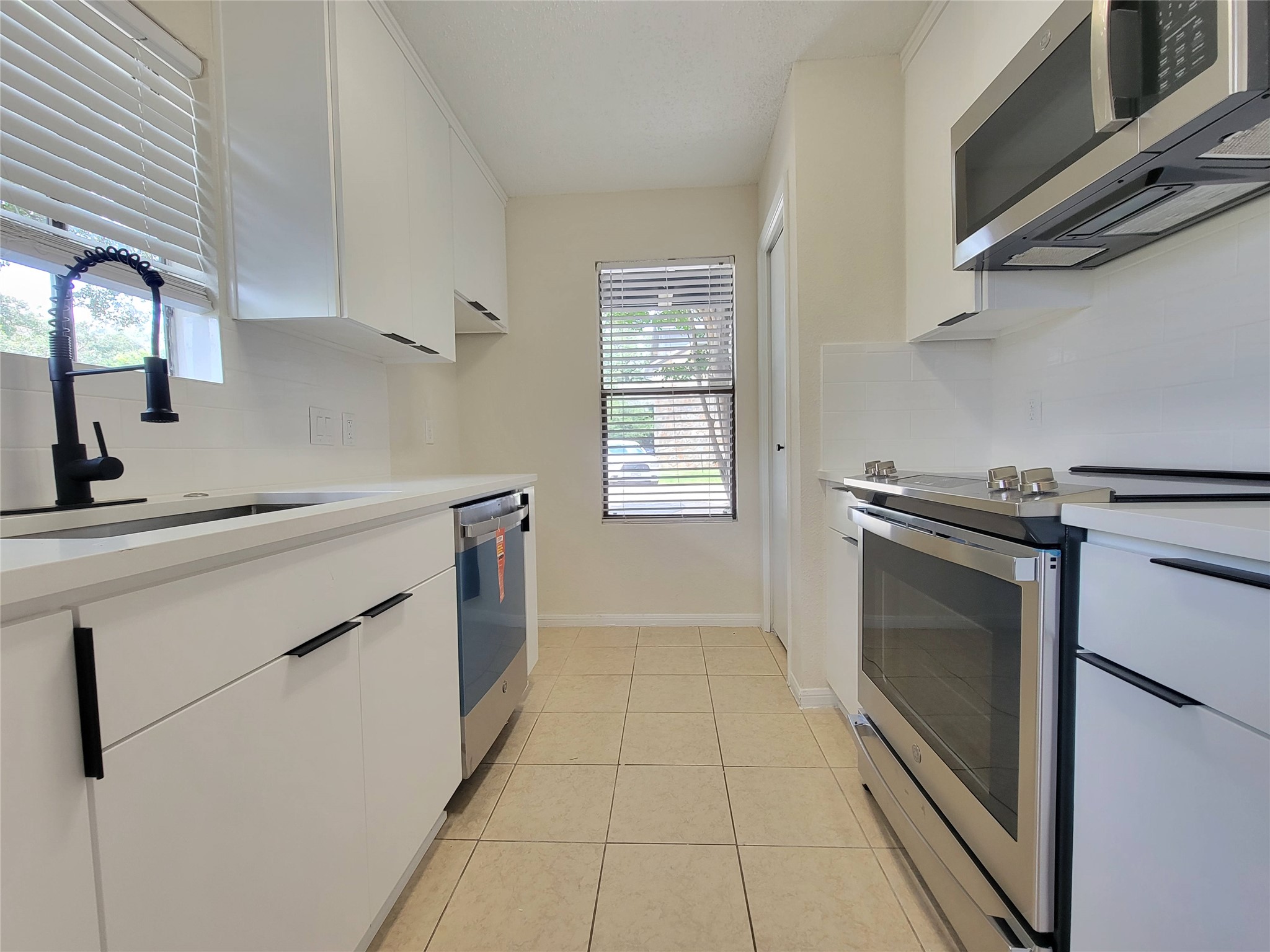 8706 Schick Road, Unit A Austin, TX 78729 - Photo 9 of 33 A well-appointed kitchen features stainless steel appliances, ample white cabinetry, and durable tile flooring.