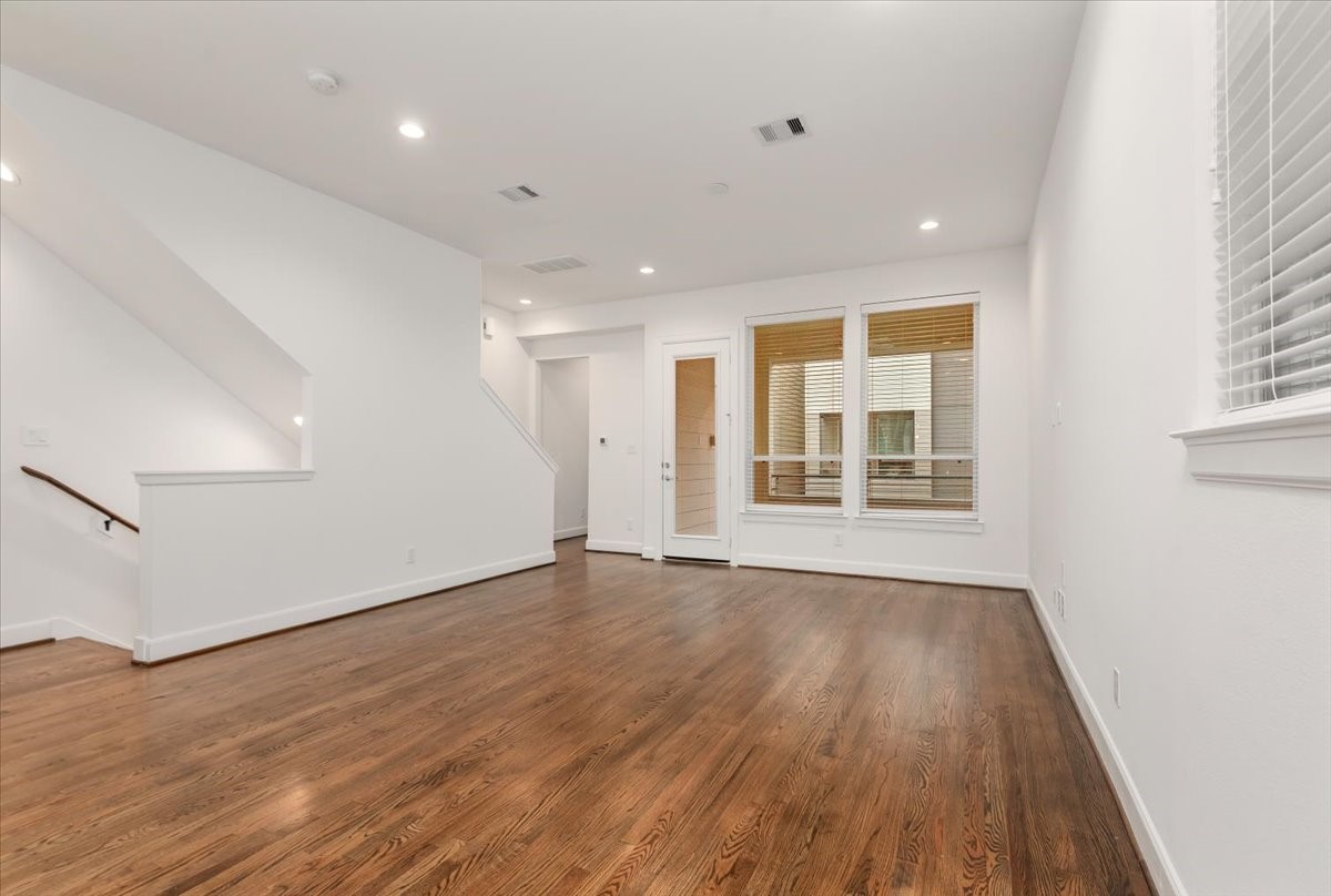 2777 Clinton Drive Houston, TX 77020 - Photo 16 of 37 Bright, open living space with hardwood floors and a modern design. It features a staircase, recessed lighting, and large windows that let in plenty of natural light, creating an inviting atmosphere.