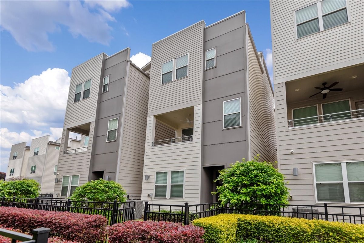 2777 Clinton Drive Houston, TX 77020 - Photo 2 of 37 Modern three-story townhouse with a sleek exterior, featuring large windows and a balcony. The property is surrounded by well-maintained landscaping and a fenced yard, offering a contemporary urban living experience.