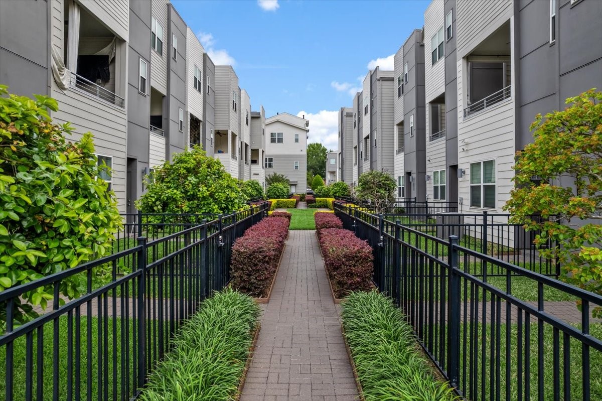 2777 Clinton Drive Houston, TX 77020 - Photo 33 of 37 Modern courtyard with a landscaped walkway, flanked by greenery and secure black metal fencing.