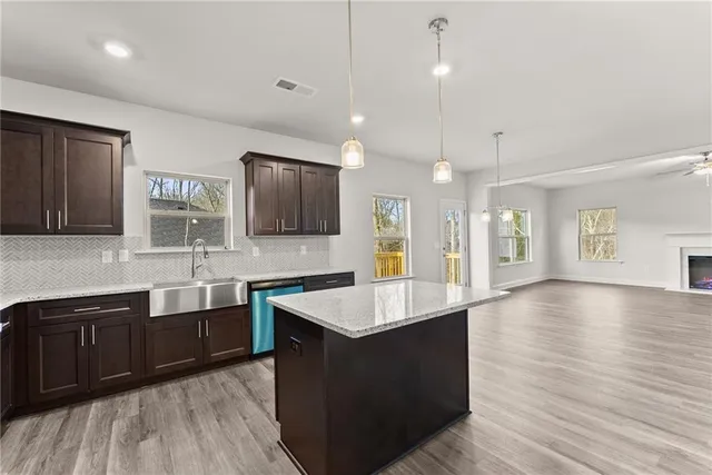a large kitchen with stainless steel appliances a large counter top a sink and a wooden floor