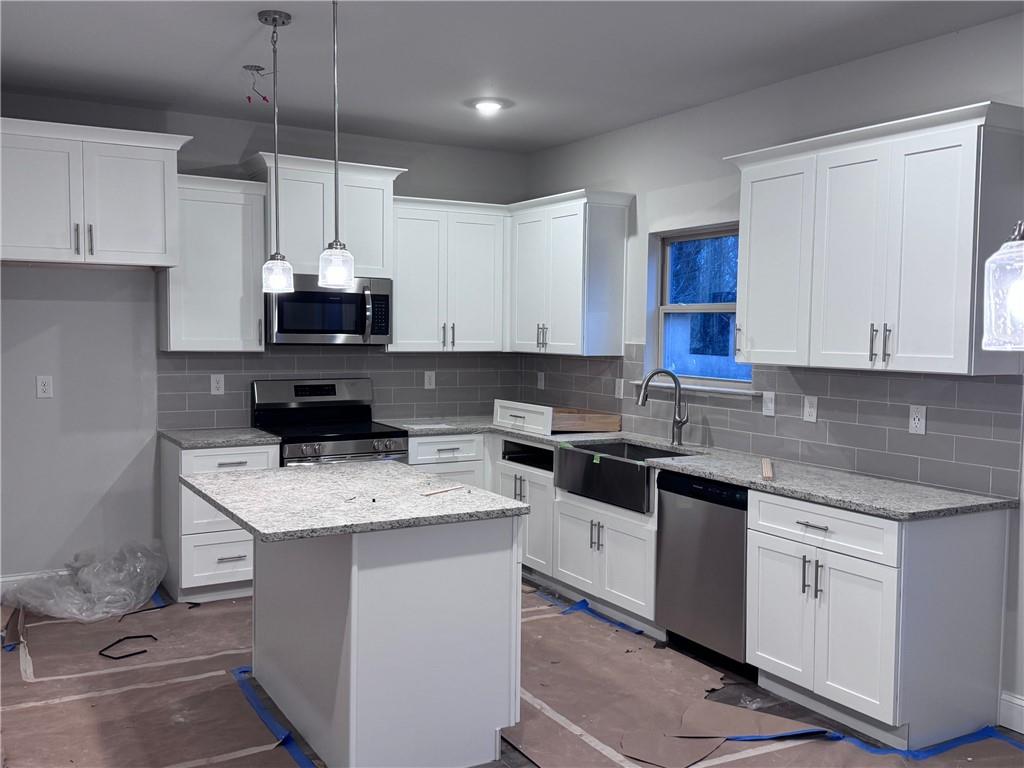 484 Magnolia Grove Place Cornelia, GA 30531 - Photo 3 of 35 a kitchen with kitchen island granite countertop stainless steel appliances a sink a stove a microwave a center island and cabinets