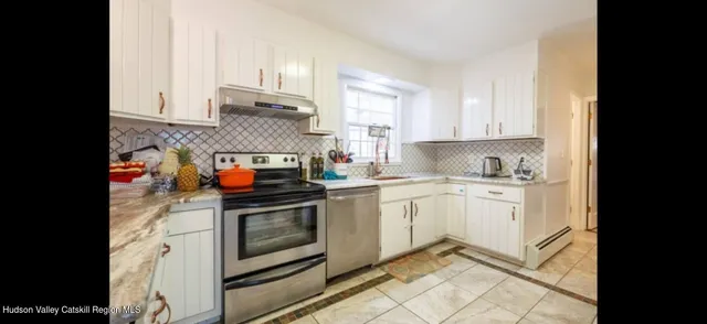 a kitchen with stainless steel appliances granite countertop a stove and white cabinets