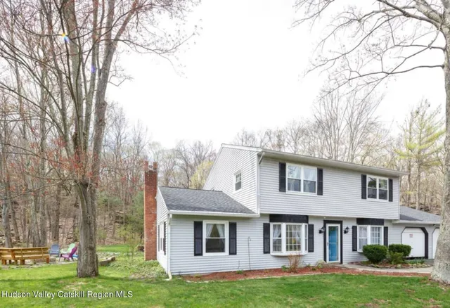 a front view of a house with a garden and trees