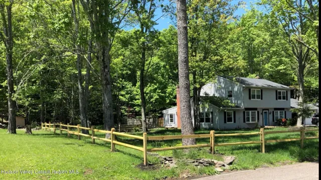 a view of house with a big yard and large trees
