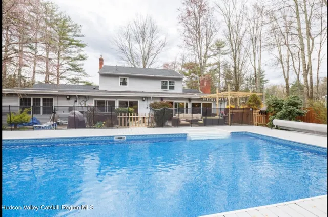 a view of house with yard outdoor seating and covered with trees