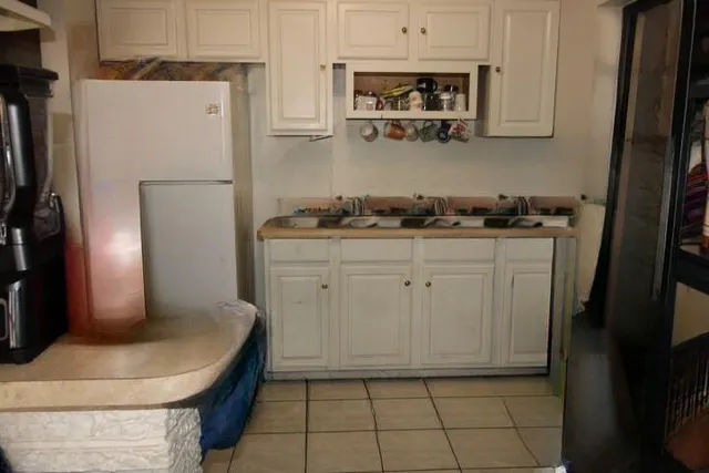 a kitchen with stainless steel appliances granite countertop a refrigerator a stove a sink and white cabinets