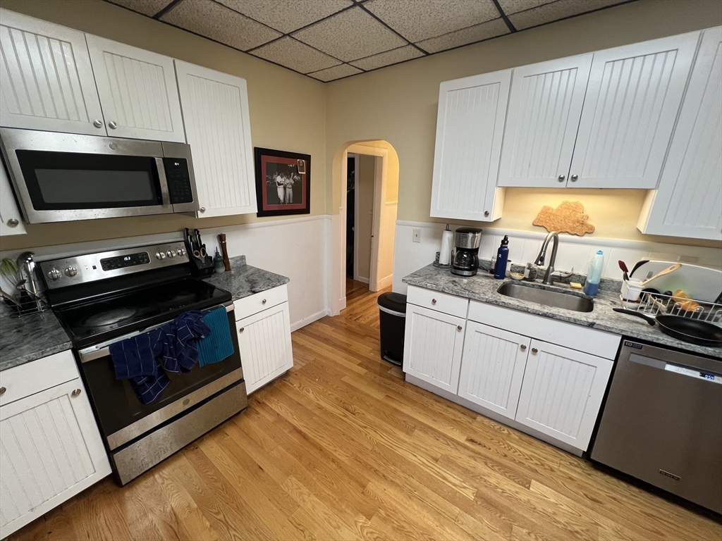 29 Cameron Avenue, Unit 1 Somerville, MA 02144 - Photo 12 of 16 a kitchen with stainless steel appliances a stove a sink a refrigerator white cabinets and wooden floor