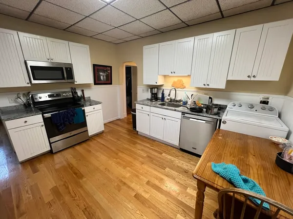 a kitchen with stainless steel appliances granite countertop a stove a sink dishwasher and a refrigerator with wooden floor