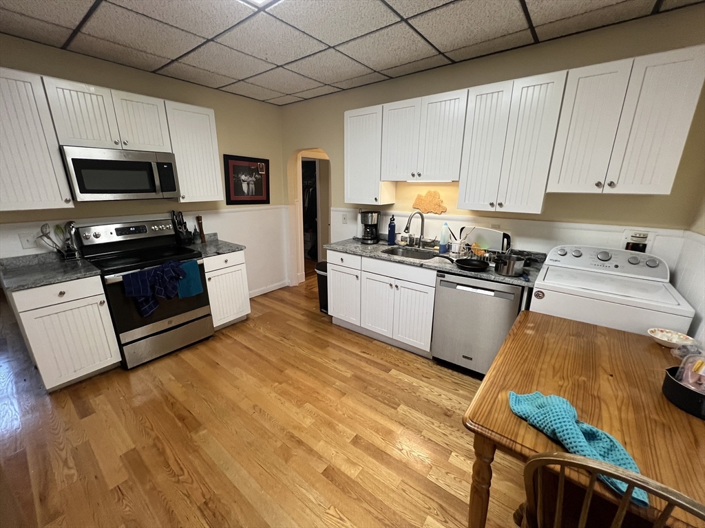 29 Cameron Avenue, Unit 1 Somerville, MA 02144 - Photo 9 of 16 a kitchen with stainless steel appliances granite countertop a stove a sink dishwasher and a refrigerator with wooden floor