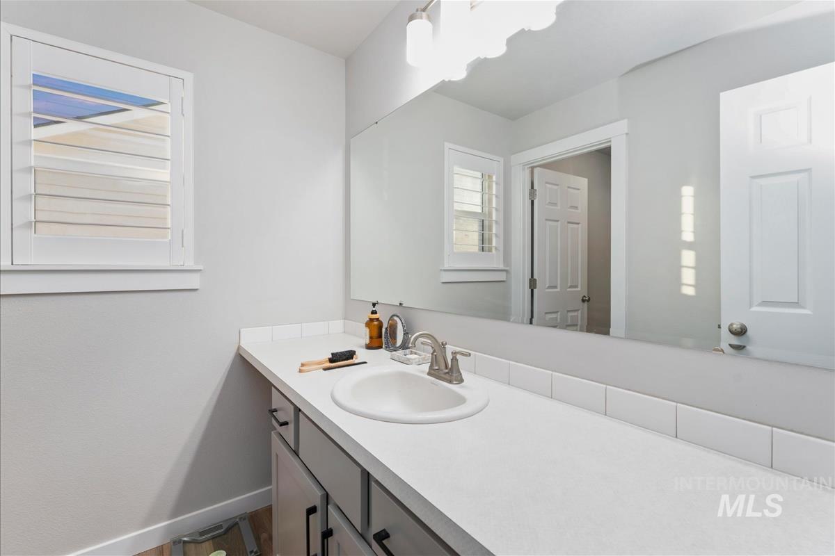 15451 Lutsen Avenue Caldwell, ID 83607 - Photo 22 of 39 Bathroom featuring a double vanity with grey cabinetry, brushed nickel hardware, and white countertops