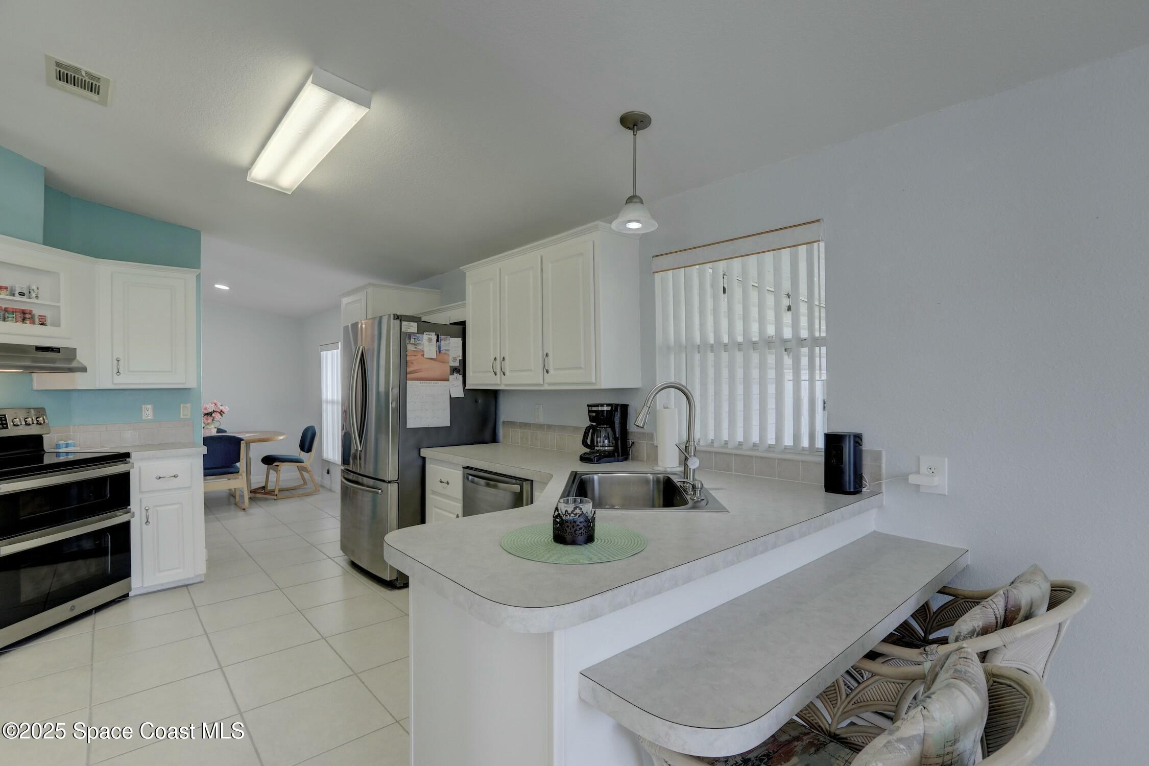1124 Barefoot Circle Barefoot Bay, FL 32976 - Photo 51 of 79 a kitchen with a sink a stove and chairs