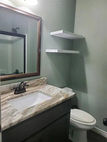 a bathroom with a granite countertop toilet sink and mirror