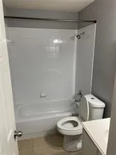 a white toilet sitting next to a bath tub