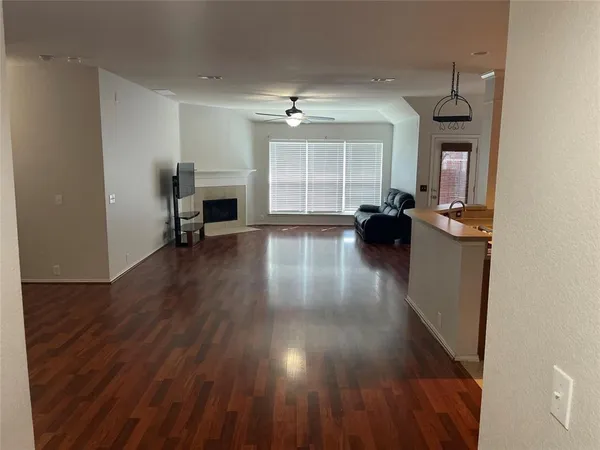 an empty room with wooden floor fireplace and windows