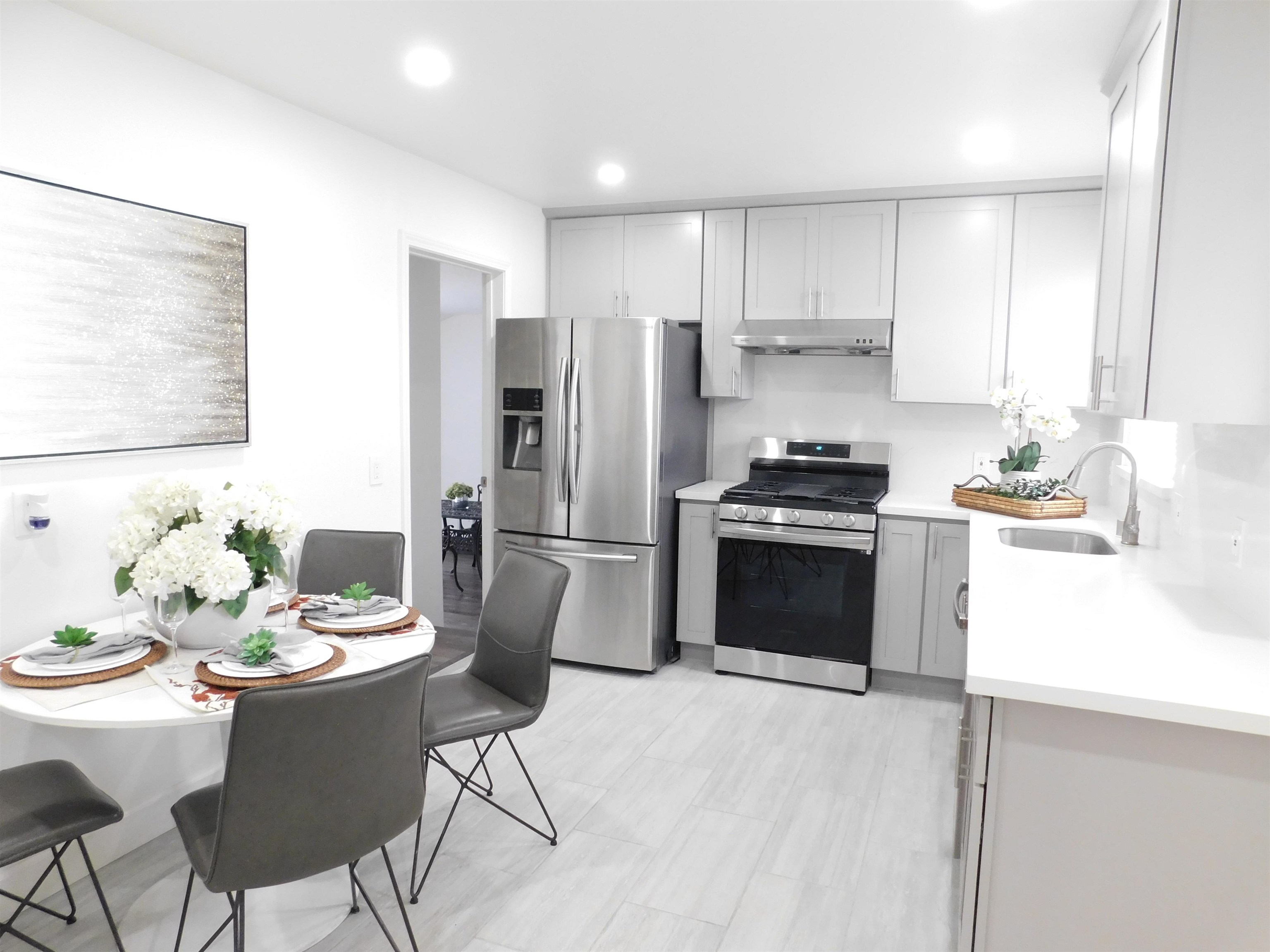 15018 Edgemoor Street San Leandro, CA 94579 - Photo 8 of 13 a kitchen with stainless steel appliances a stove a sink a microwave a refrigerator and white cabinets with wooden floor