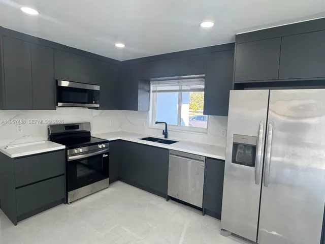 a kitchen with stainless steel appliances granite countertop a refrigerator and a stove