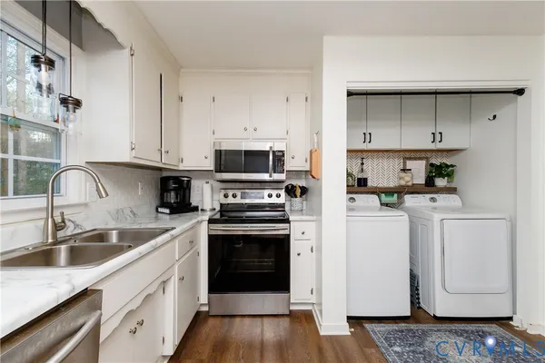 a kitchen with white cabinets sink and stainless steel appliances