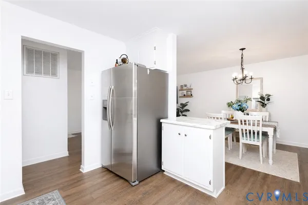 a kitchen with stainless steel appliances a refrigerator a stove a dining table and chairs with wooden floor