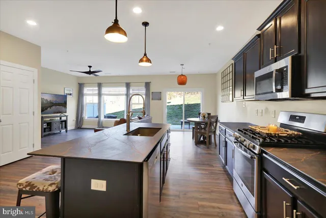 a kitchen with stainless steel appliances granite countertop a stove top oven a sink a dining table and chairs with wooden floor