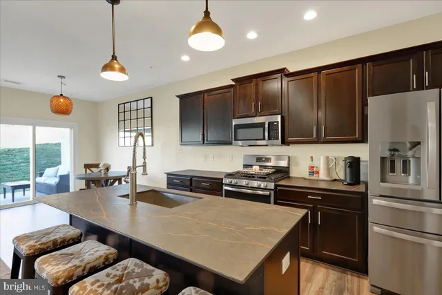 a kitchen with stainless steel appliances granite countertop a sink refrigerator stove and microwave