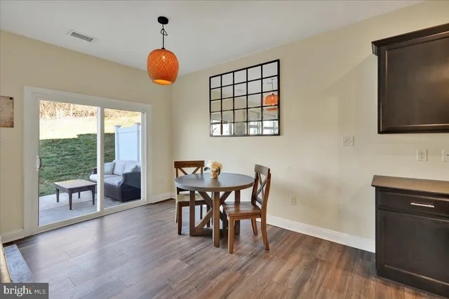 a dining room with wooden floor a chandelier a glass table and chairs