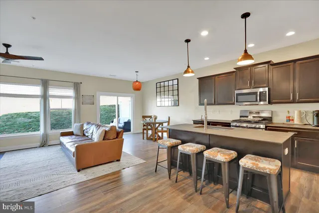 a kitchen with stainless steel appliances granite countertop a stove top oven a sink dishwasher a dining table and chairs with wooden floor