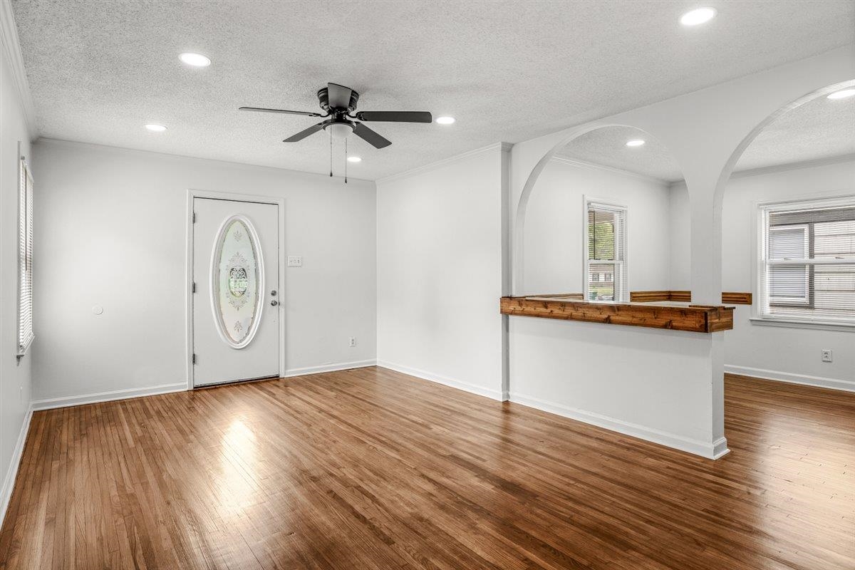 1244 Wells Station Road Memphis, TN 38122 - Photo 9 of 36 Unfurnished living room with ceiling fan, a textured ceiling, recessed lighting, dark wood-type flooring, and ornamental molding