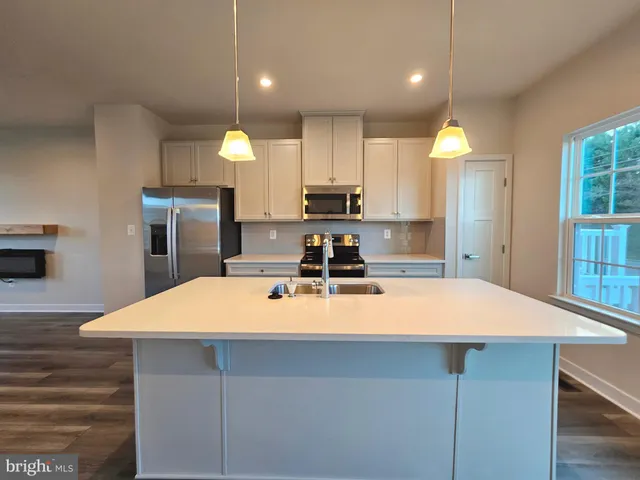 a kitchen that has a sink a stove and wooden floor