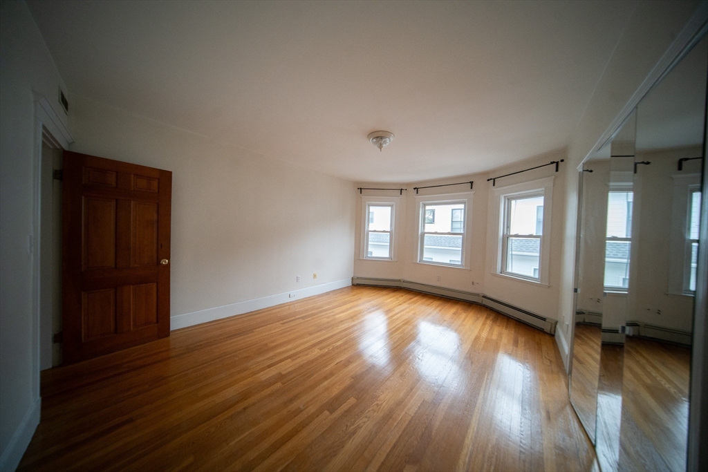 208 Rawson Road, Unit 2 Brookline, MA 02445 - Photo 16 of 33 a view of an empty room with wooden floor and a window
