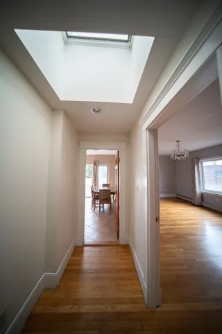 a view of a hallway with wooden floor and a living room