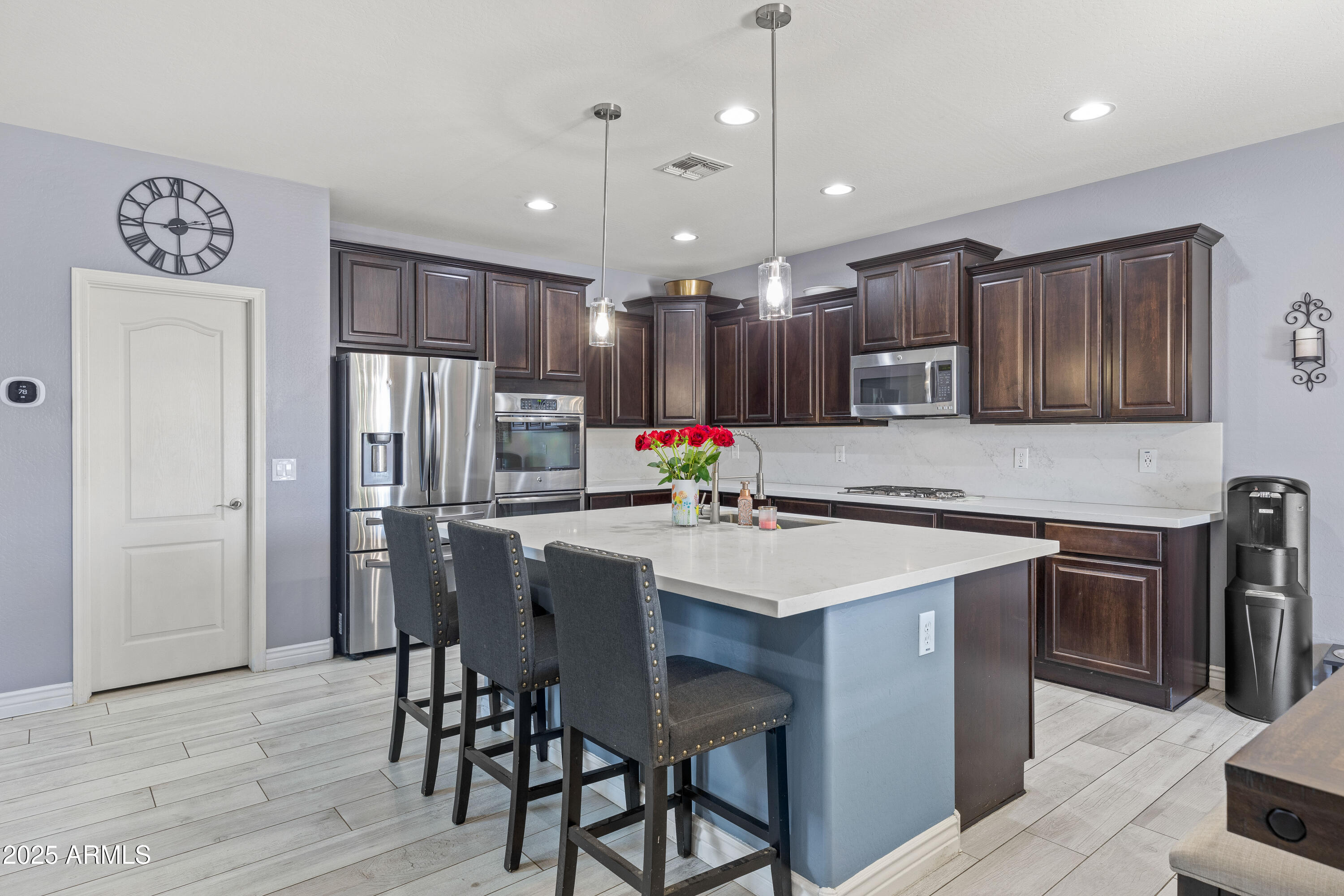 18649 West Williams Street Goodyear, AZ 85338 - Photo 9 of 42 a kitchen with stainless steel appliances a dining table chairs refrigerator and microwave