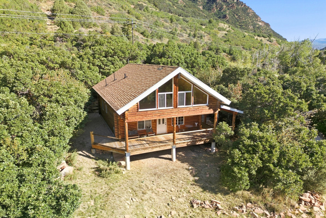 2640 East Weber Canyon Road Oakley, UT 84055 - Photo 1 of 56 Log cabin exterior with a pitched roof, expansive front deck, and a wall of windows