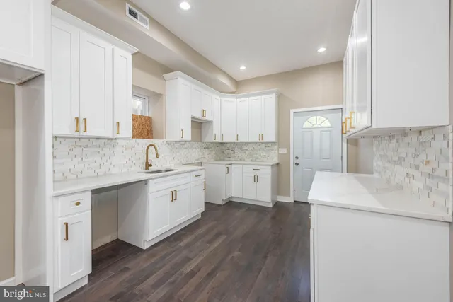 a kitchen with a sink white cabinets and white appliances