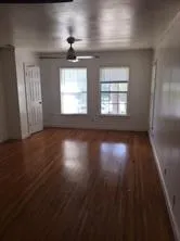 an empty room with wooden floor chandelier and windows