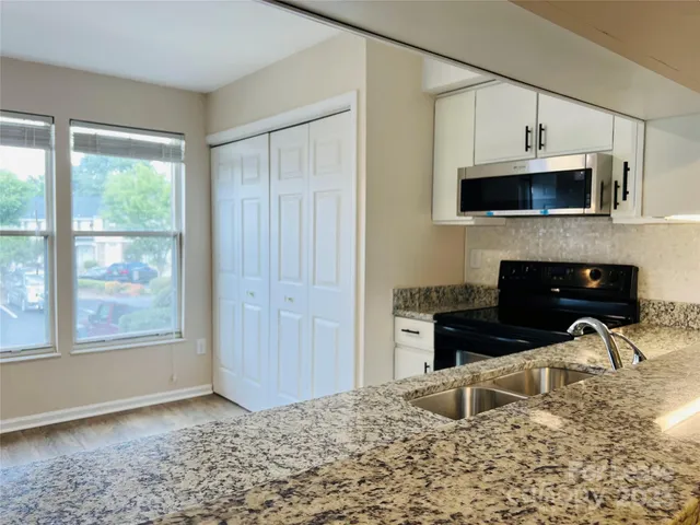 a kitchen with stainless steel appliances granite countertop a stove a sink and a microwave