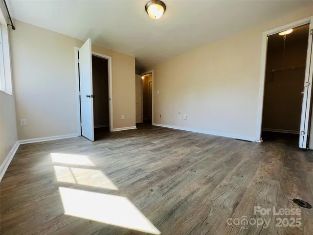 a view of an empty room with wooden floor and closet