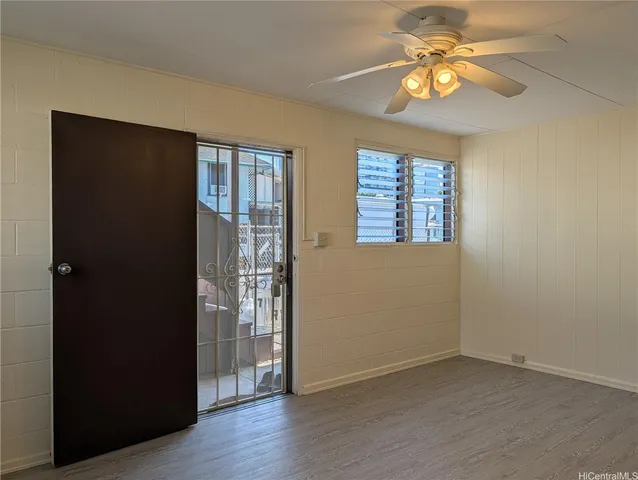 an empty room with wooden floor closet and windows