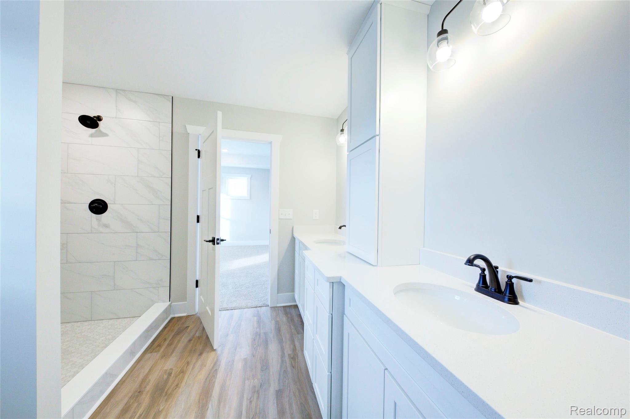 579 Round Rock (moh80) Howell, MI 48843 - Photo 22 of 42 Full bathroom with double vanity, light wood finished floors, and tiled shower