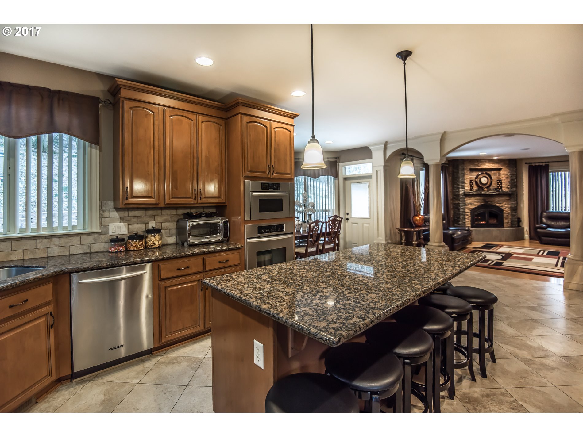 17980 Southeast Vogel Road Damascus, OR 97089 - Photo 11 of 32 a kitchen with stainless steel appliances kitchen island granite countertop a table chairs in it and wooden floors