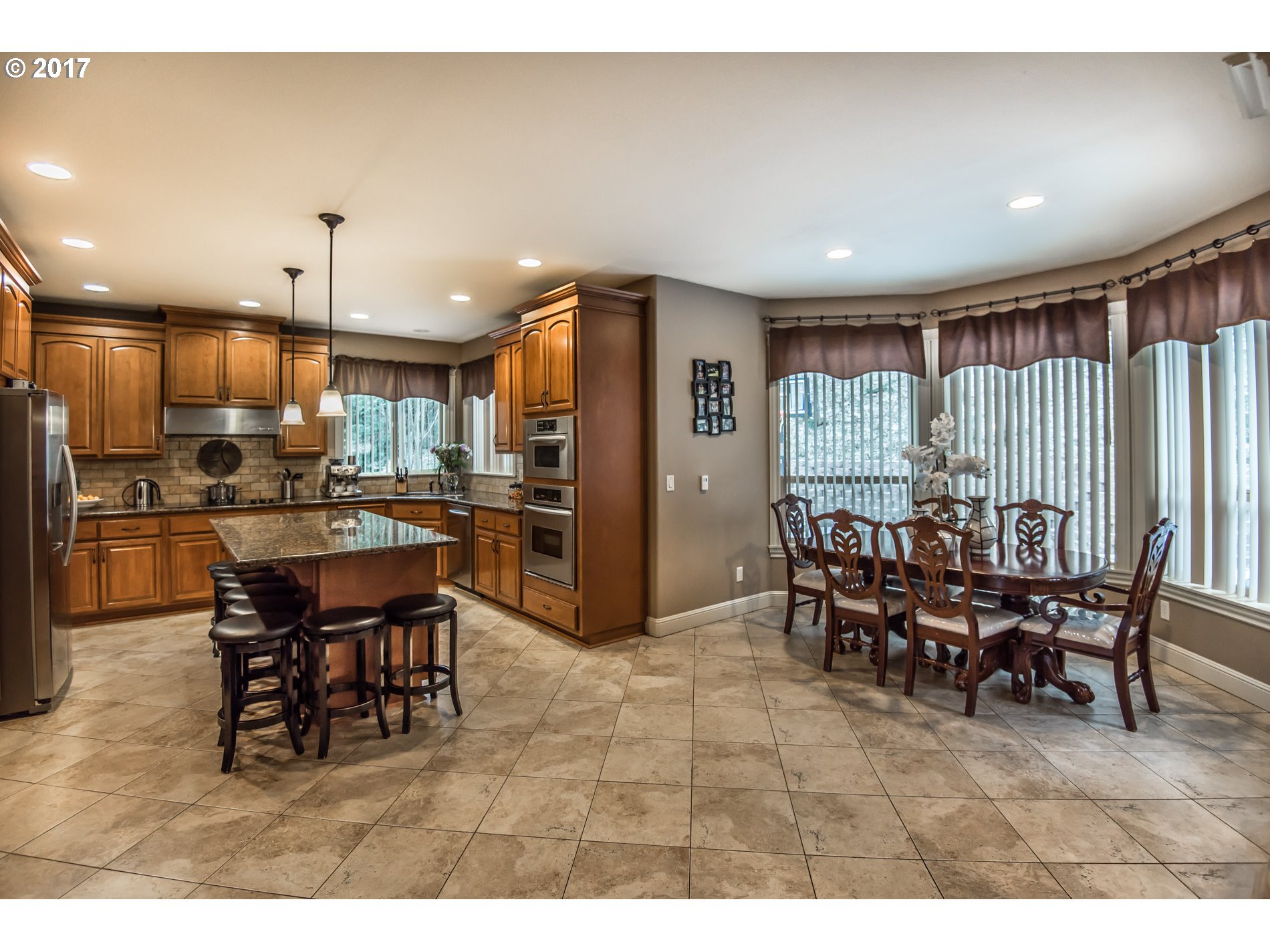 17980 Southeast Vogel Road Damascus, OR 97089 - Photo 8 of 32 a dining room with stainless steel appliances kitchen island granite countertop a dining table chairs and a refrigerator