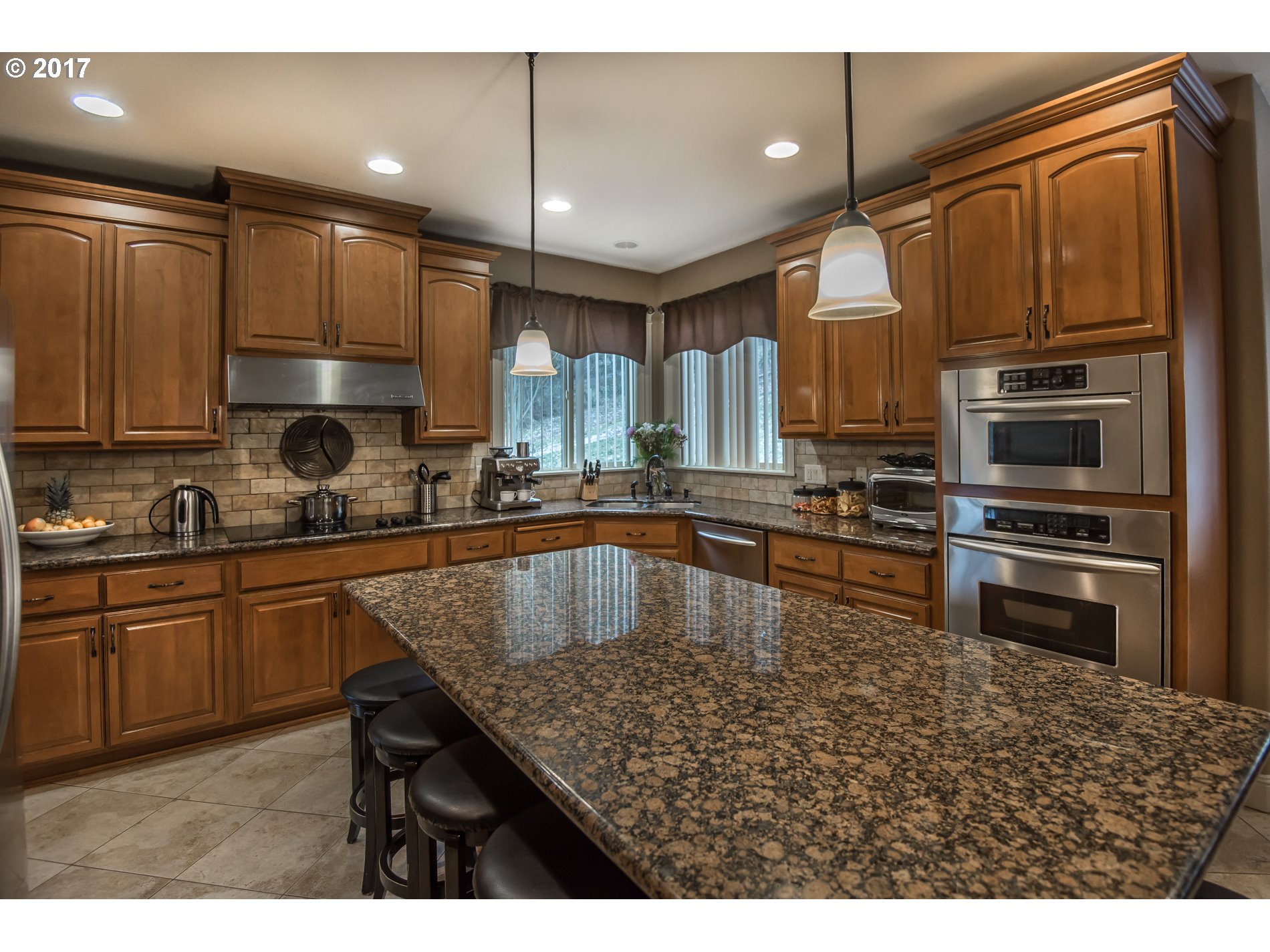 17980 Southeast Vogel Road Damascus, OR 97089 - Photo 10 of 32 a kitchen with kitchen island granite countertop a stove a sink and a microwave