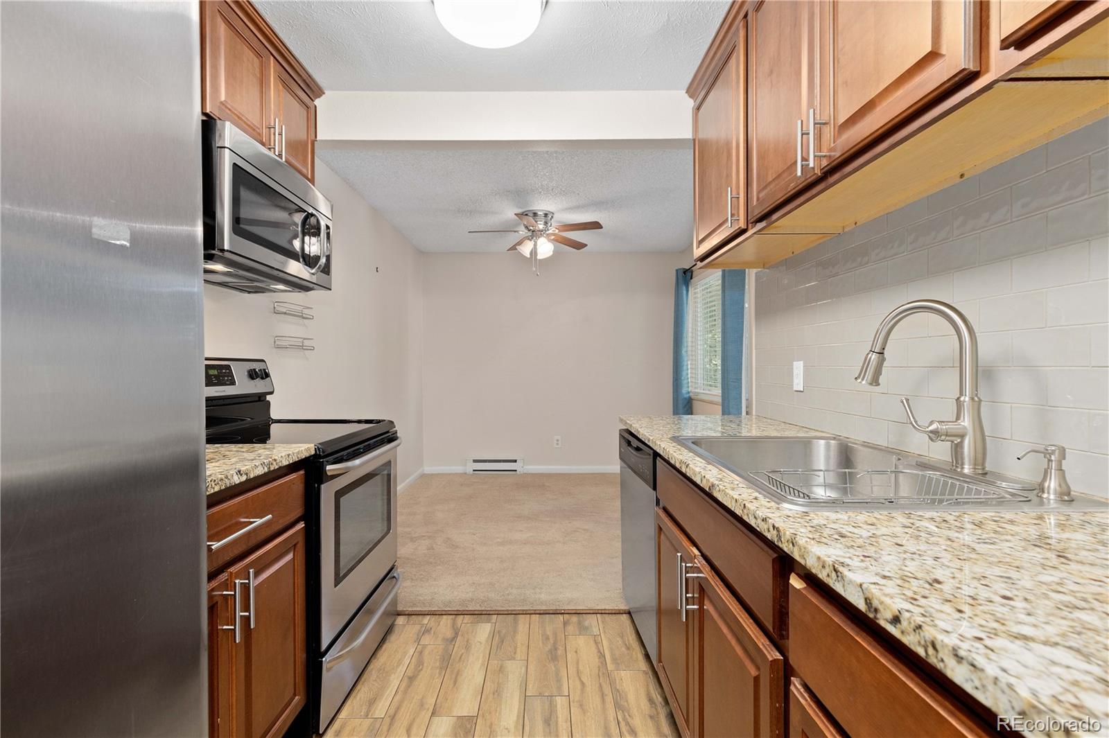 4068 South Atchison Way, Unit 202 Aurora, CO 80014 - Photo 15 of 33 a kitchen with granite countertop stainless steel appliances a sink stove and refrigerator